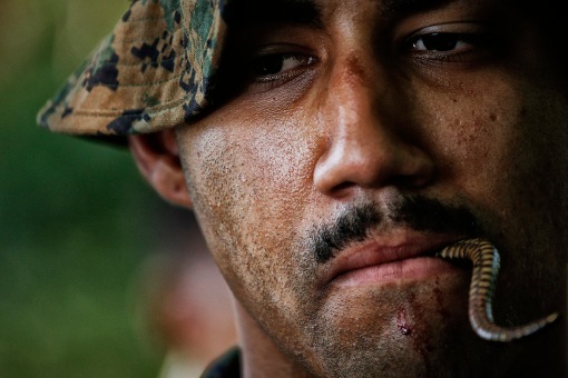 A U.S. marine has a tail of dead cobra in his mouth during a jungle survival exercise with the Thai Navy as part of the "Cobra Gold 2013" joint military exercise, at a military base in Chon Buri province