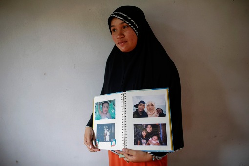 Rusnee Maeloh, a wife of Mahrosu Jantarawadee poses with a familiy album with pictures of her husband and children at their home in Duku village near Bacho in the troubled southern province of Narathiwat