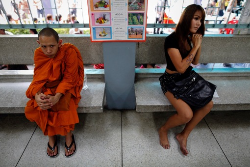 A transgender and a Buddhist monk wait aside from other youngsters  to speak to officers during the army draft held at a school in Klong Toey, the dockside slum area in Bangkok