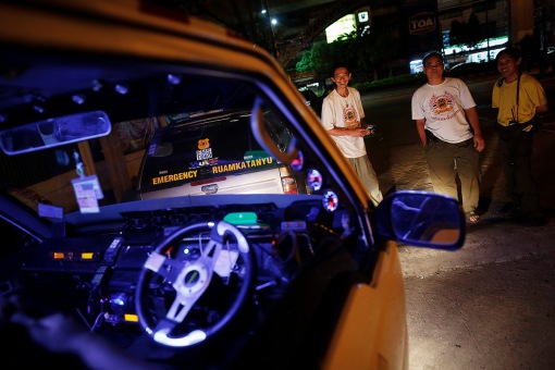 Volunteers with Ruamkatanyu, a free rescue service for accident victims stand by their vehicles as they wait for news of another accident during Songkran festival in Bangkok
