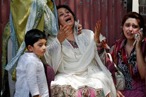 People cry as rescue workers try to save people trapped inside a burning building in central Lahore