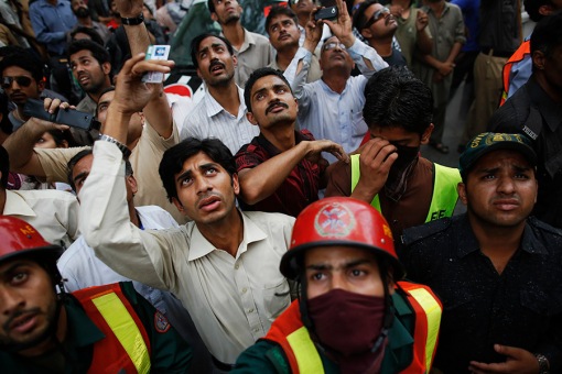 People react as rescue workers try to save people from a burning building in central Lahore