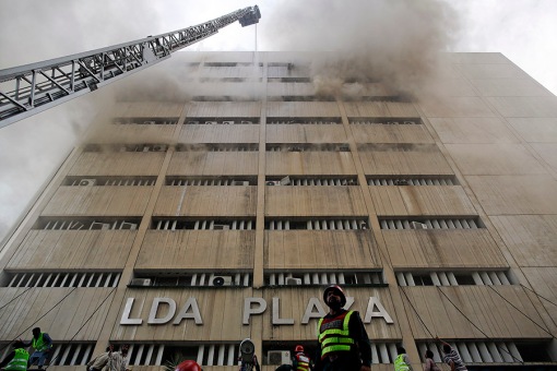 Rescue workers try to save people trapped inside a burning building in central Lahore
