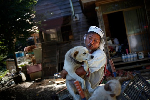 Keigo Sakamoto, holds Atom one of his 21 dogs and over 500 animals he keeps at his home in the exclusion zone near Naraha in Fukushima prefecture