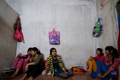 Garment workers sit on the floor of their apartment during a lunch break in one of Phnom Penh's suburbs