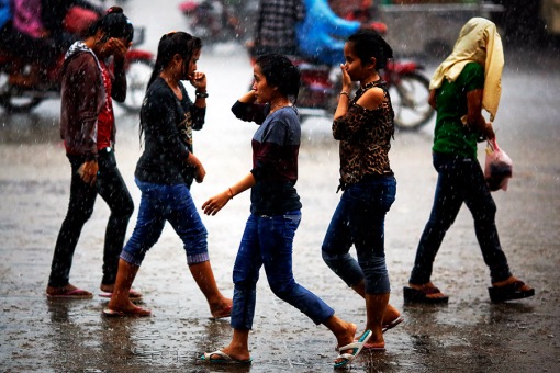 Garment workers walk in heavy rain after working at their factories at a industrial zone in one of Phnom Penh's suburbs