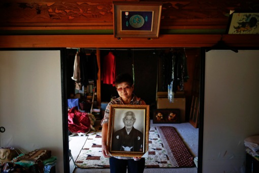 Mieko Okubo poses with portrait of her father-in-law Fumio Okubo in their house where he committed suicide in the evacuated town of Iitate in Fukushima prefecture