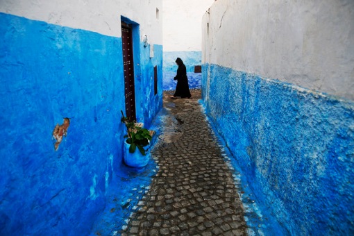 A woman makes her way between houses painted in traditional blue and white colors in Kasbah of the Oudayas, a picturesque ancient part of Rabat