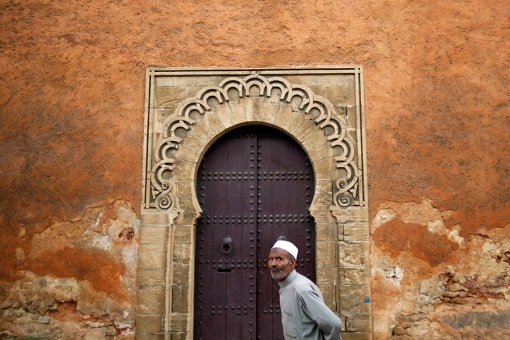 A man walks in front of doors in walls of Rabat's Medina